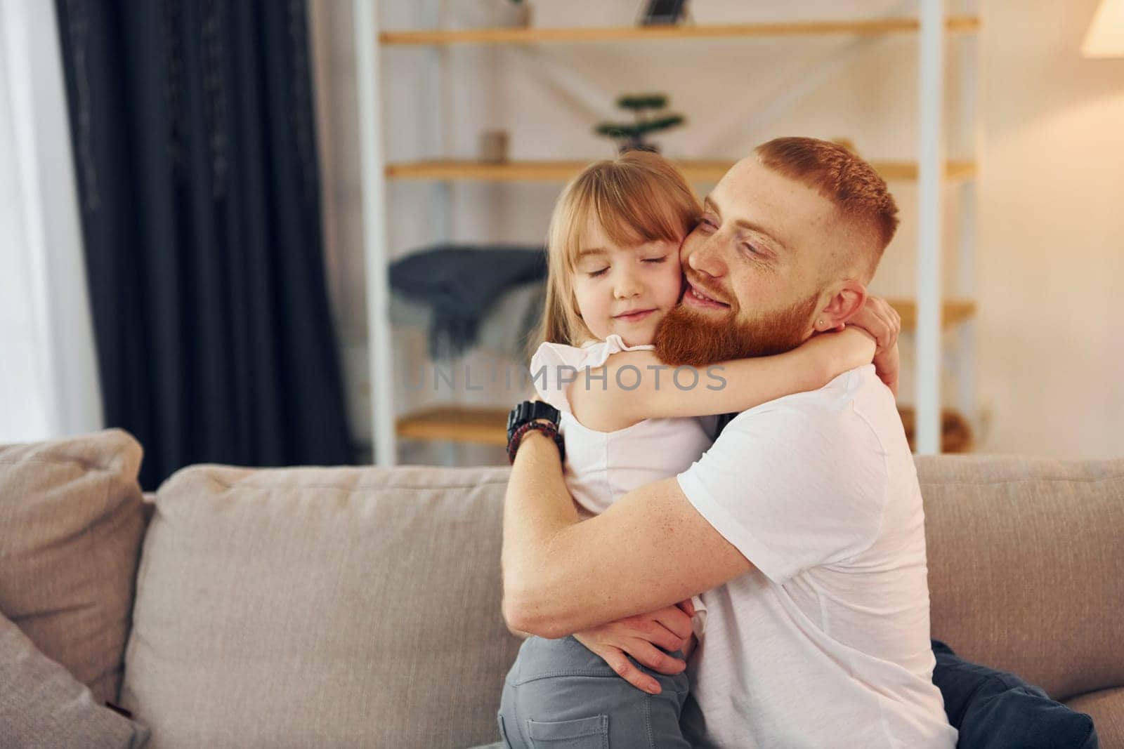 Embracing each other. Father with his little daughter is at home together.