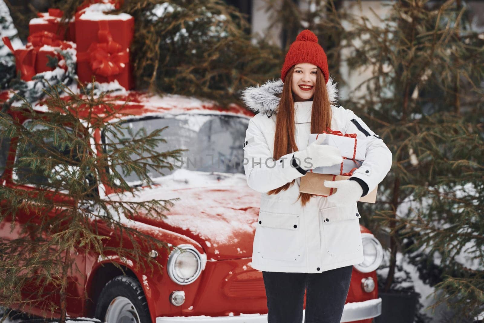 Holding present box. Happy young woman standing outdoors and celebrating christmas holidays.