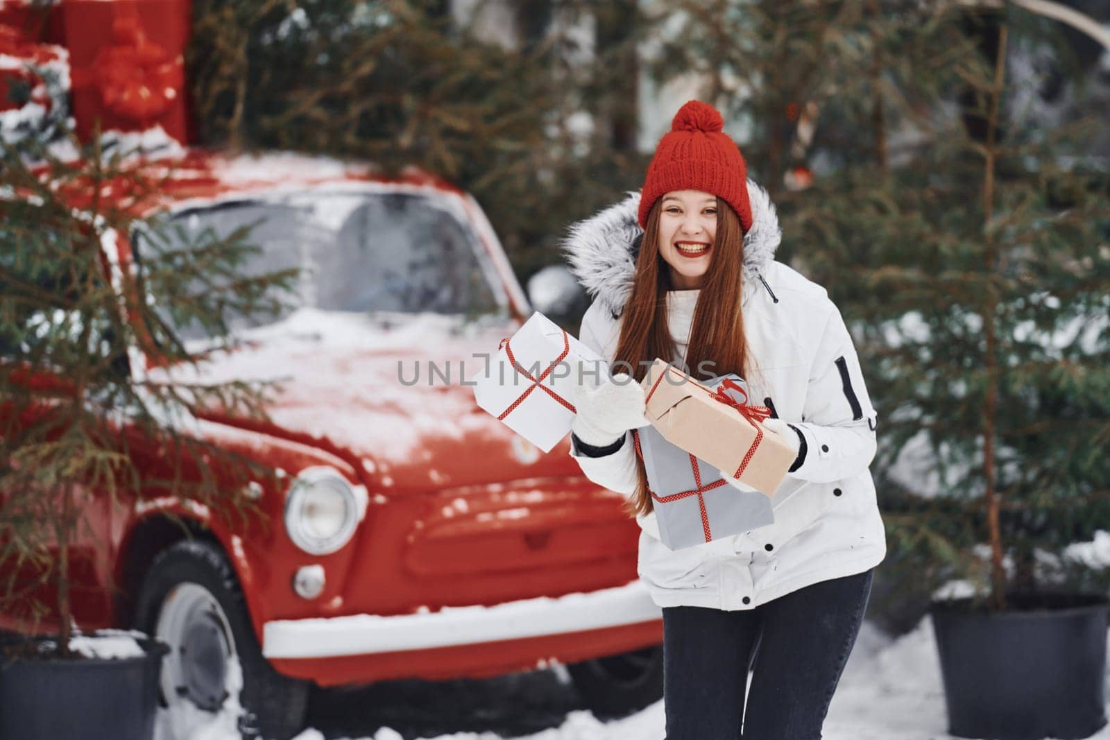 Holding present box. Happy young woman standing outdoors and celebrating christmas holidays.