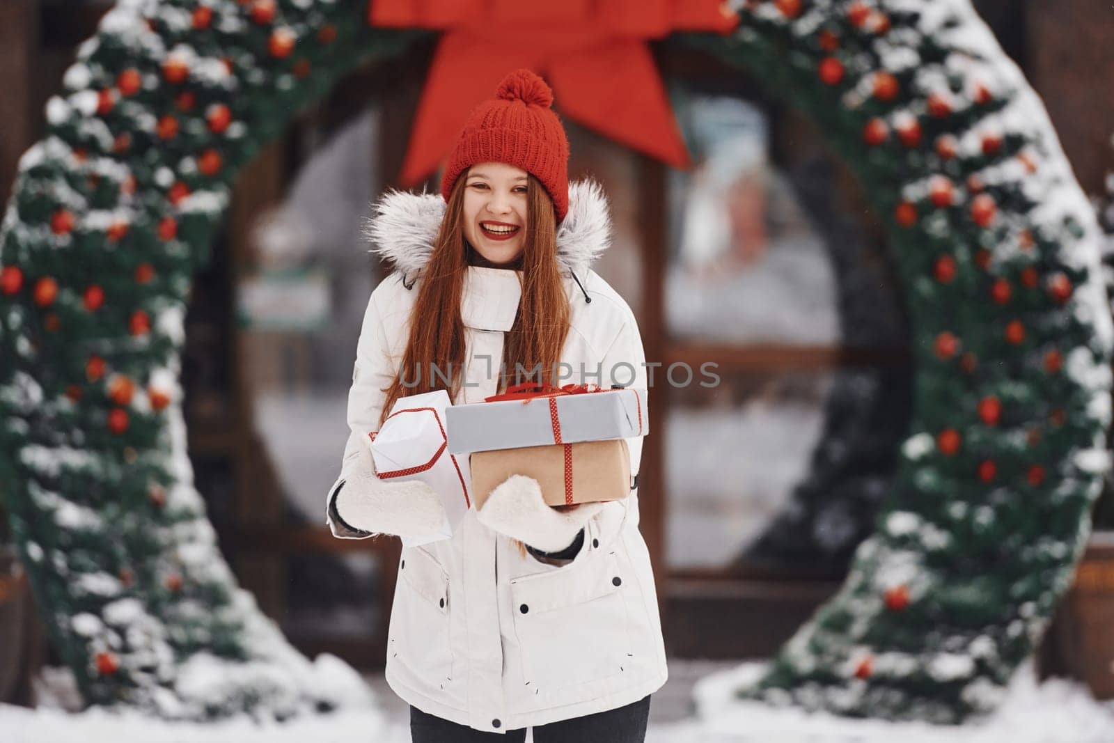 With gift box. Happy young woman standing outdoors and celebrating christmas holidays.