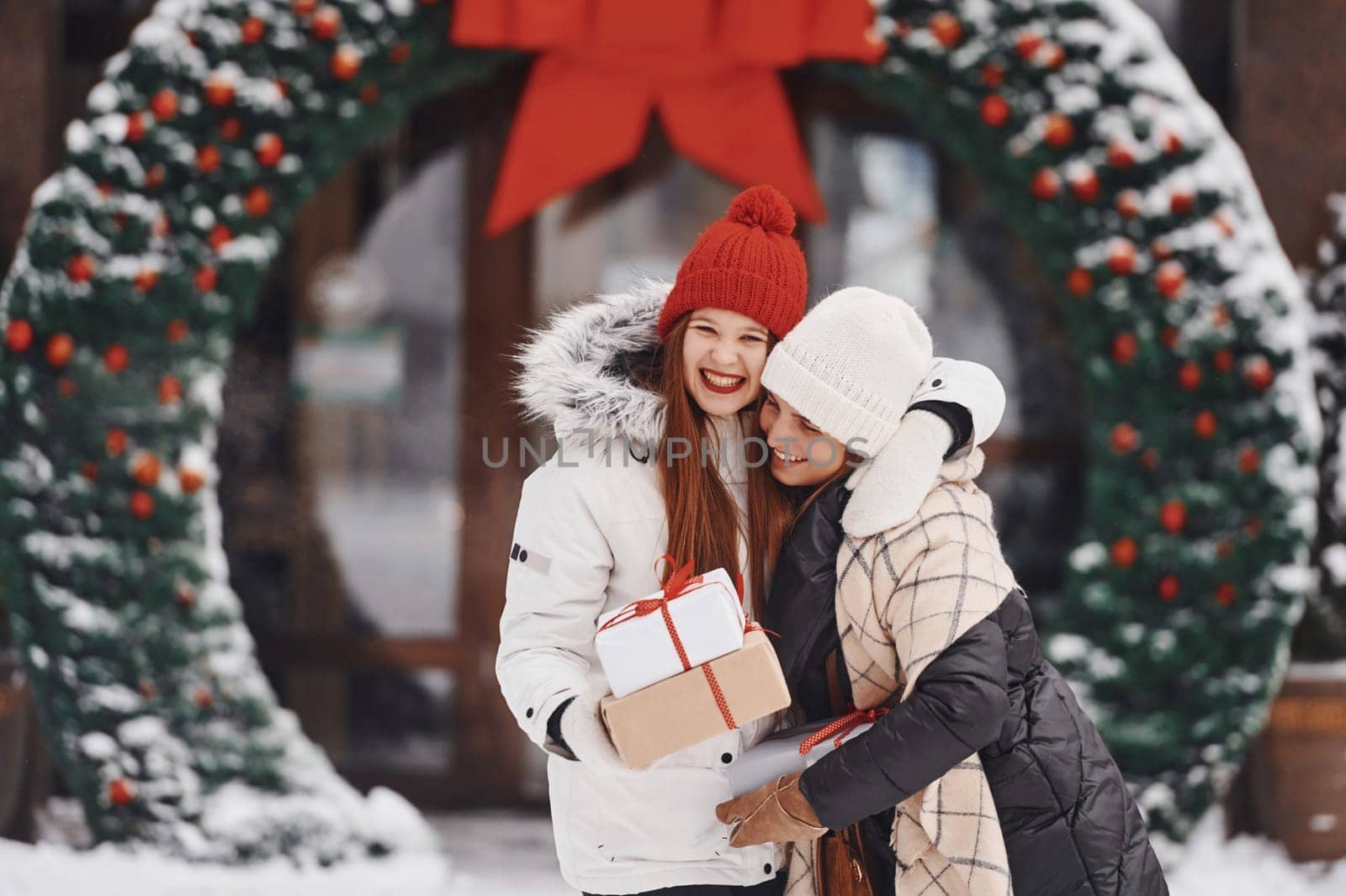 Two young women standing outdoors and celebrating christmas holidays.
