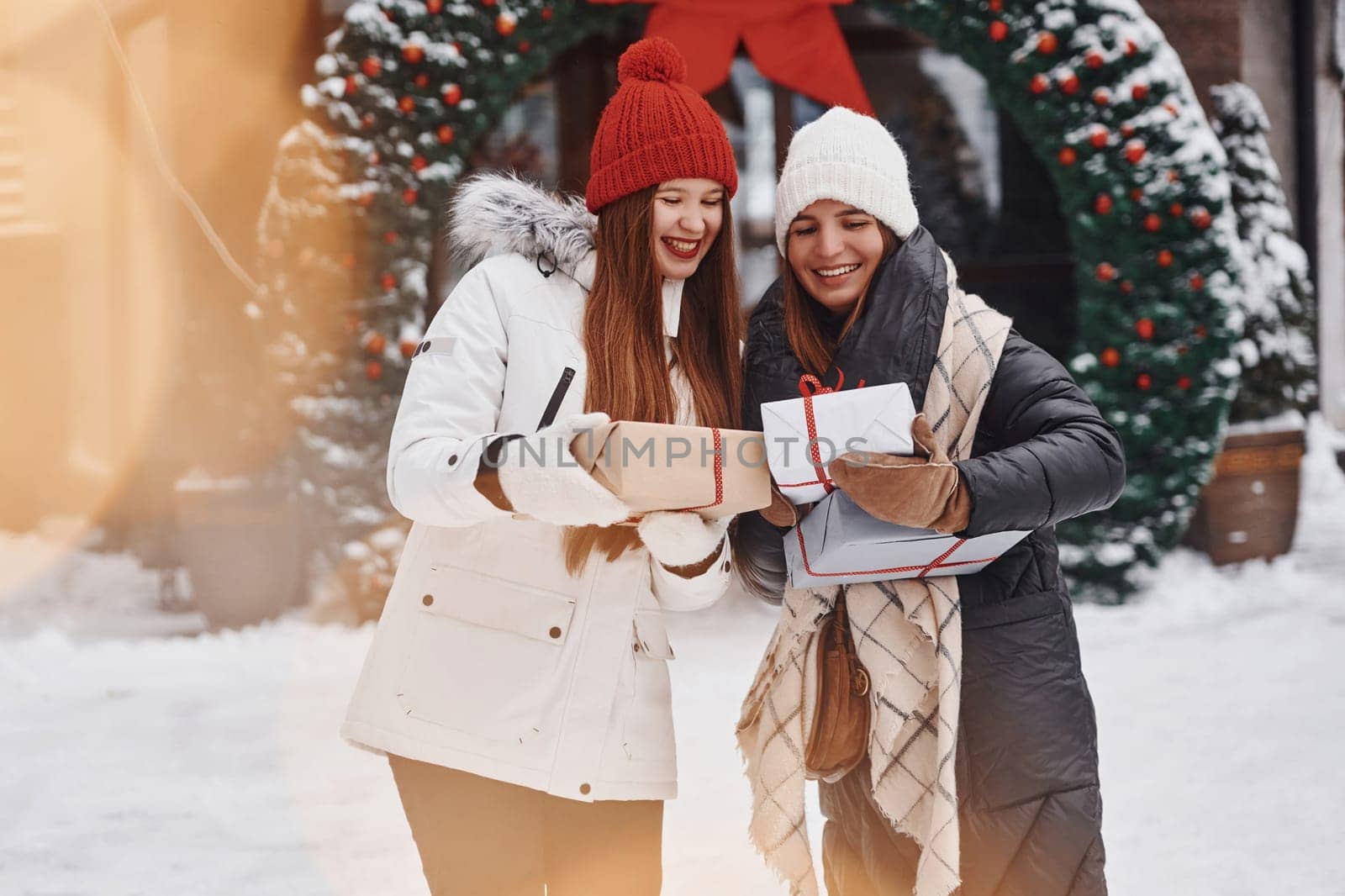 Two young women standing outdoors and celebrating christmas holidays.