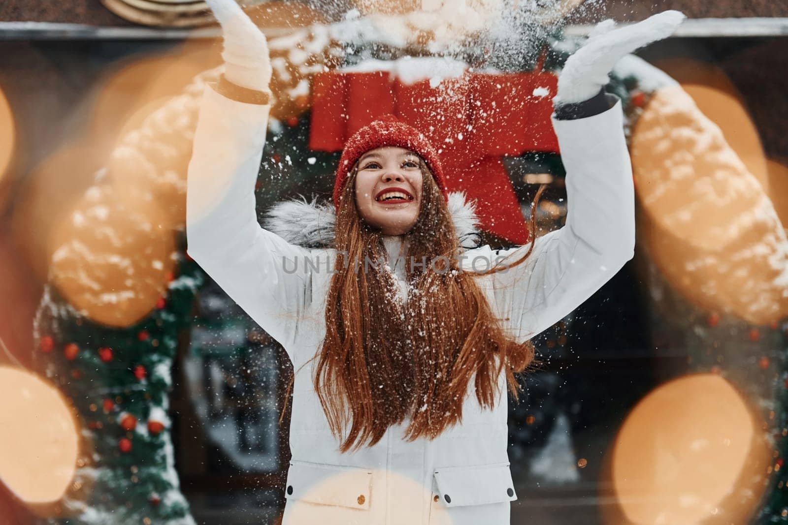 Playing with snow. Happy young woman standing outdoors and celebrating christmas holidays.