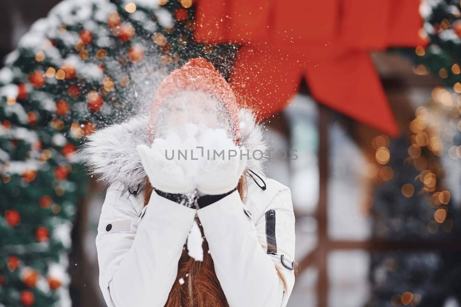 Playing with snow. Happy young woman standing outdoors and celebrating christmas holidays.