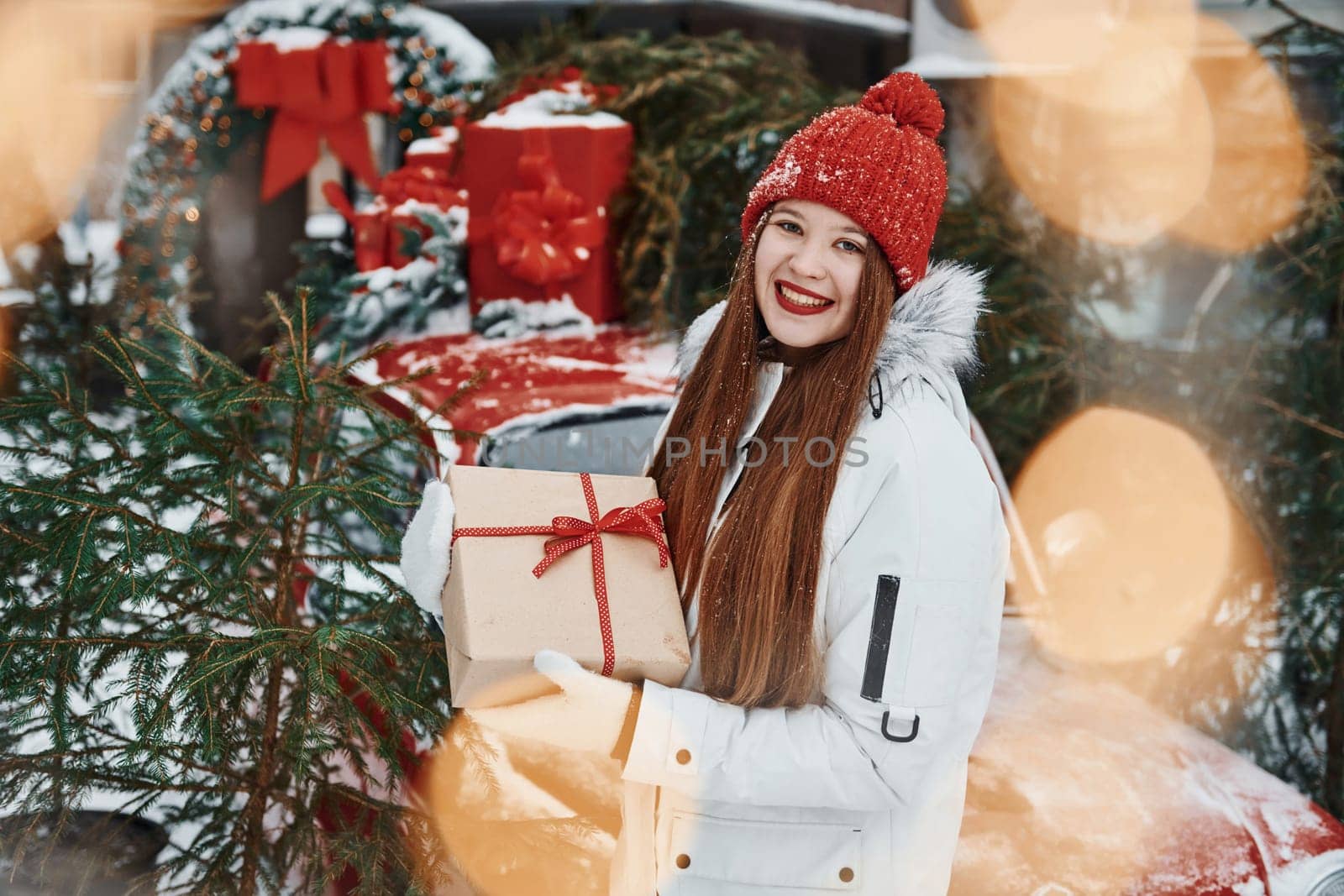 With gift box. Happy young woman standing outdoors and celebrating christmas holidays.