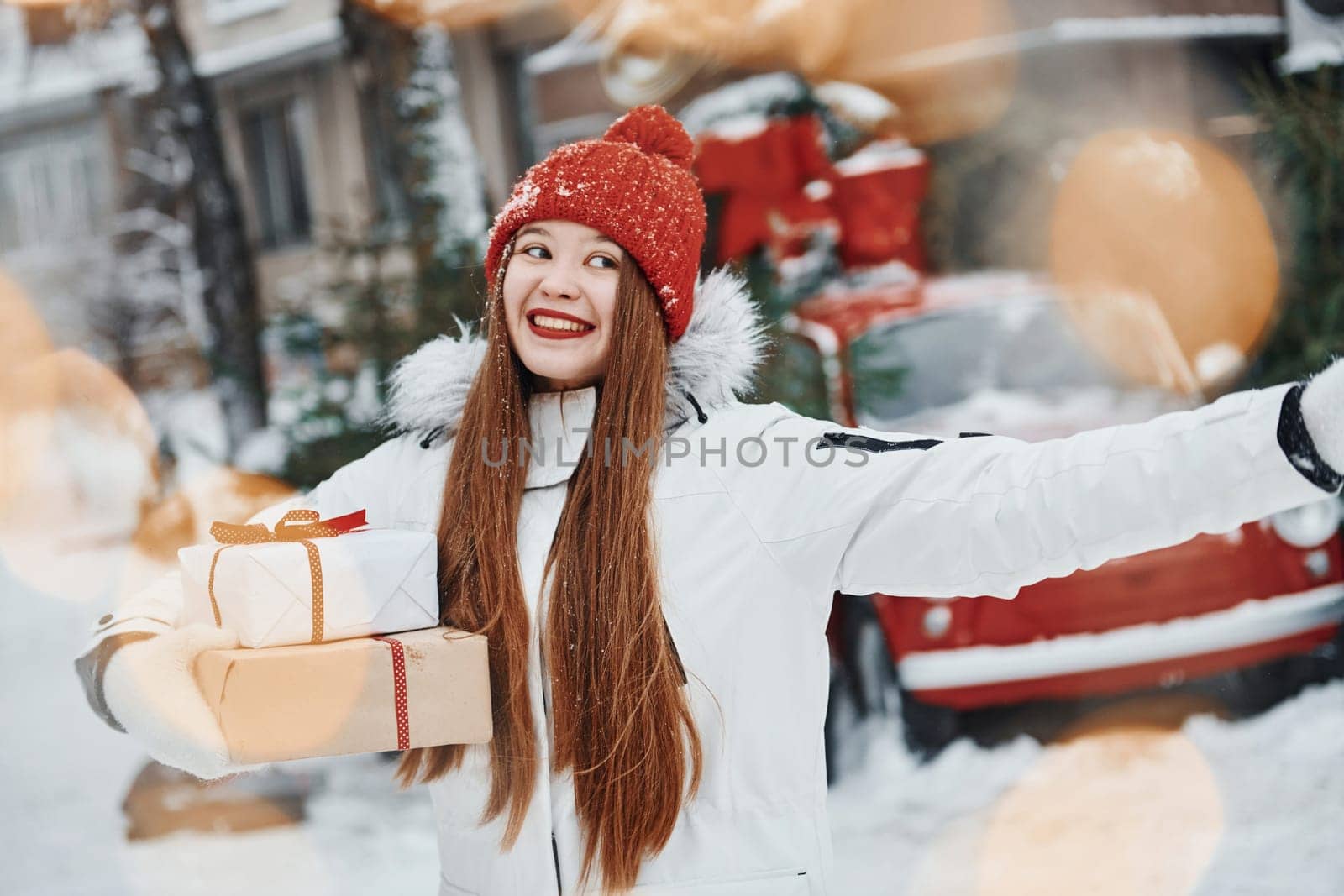 With gift box. Happy young woman standing outdoors and celebrating christmas holidays.