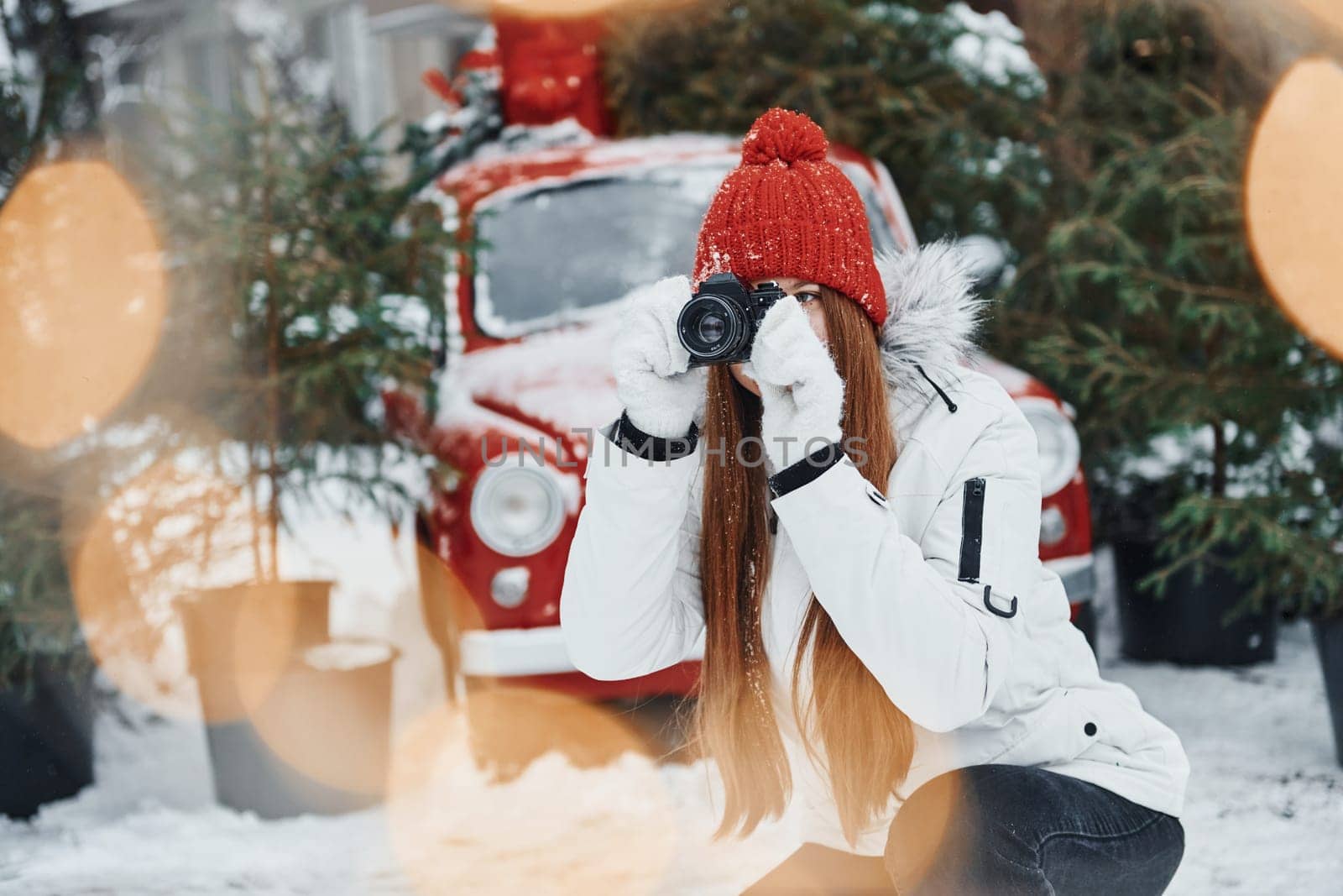 With camera in hands. Happy young woman standing outdoors and celebrating christmas holidays.