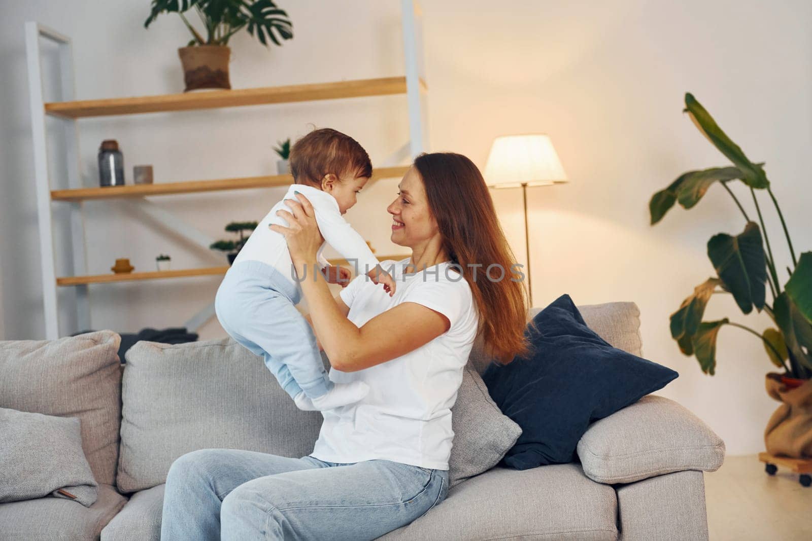 Playing on the sofa. Mother with her little daughter is at home together.