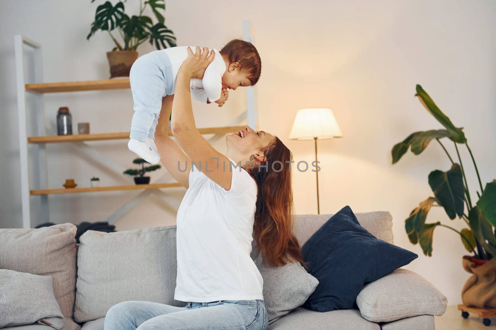 Playing on the sofa. Mother with her little daughter is at home together.