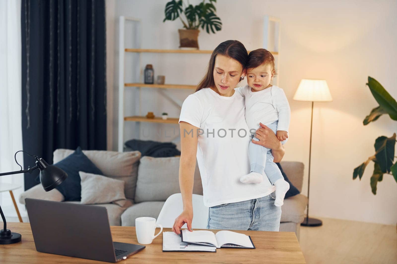 Using laptop. Mother with her little daughter is at home together.