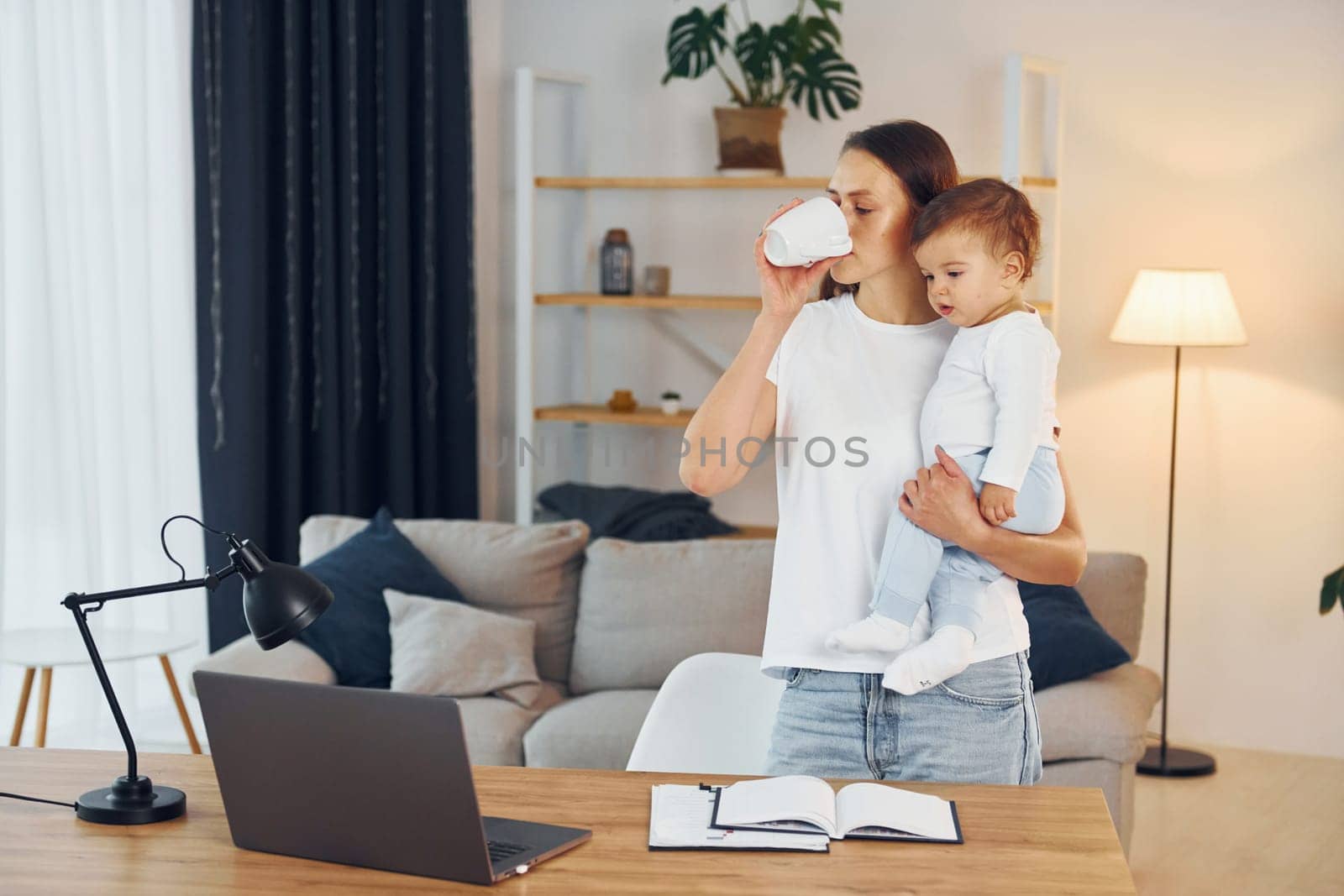 Using laptop. Mother with her little daughter is at home together.
