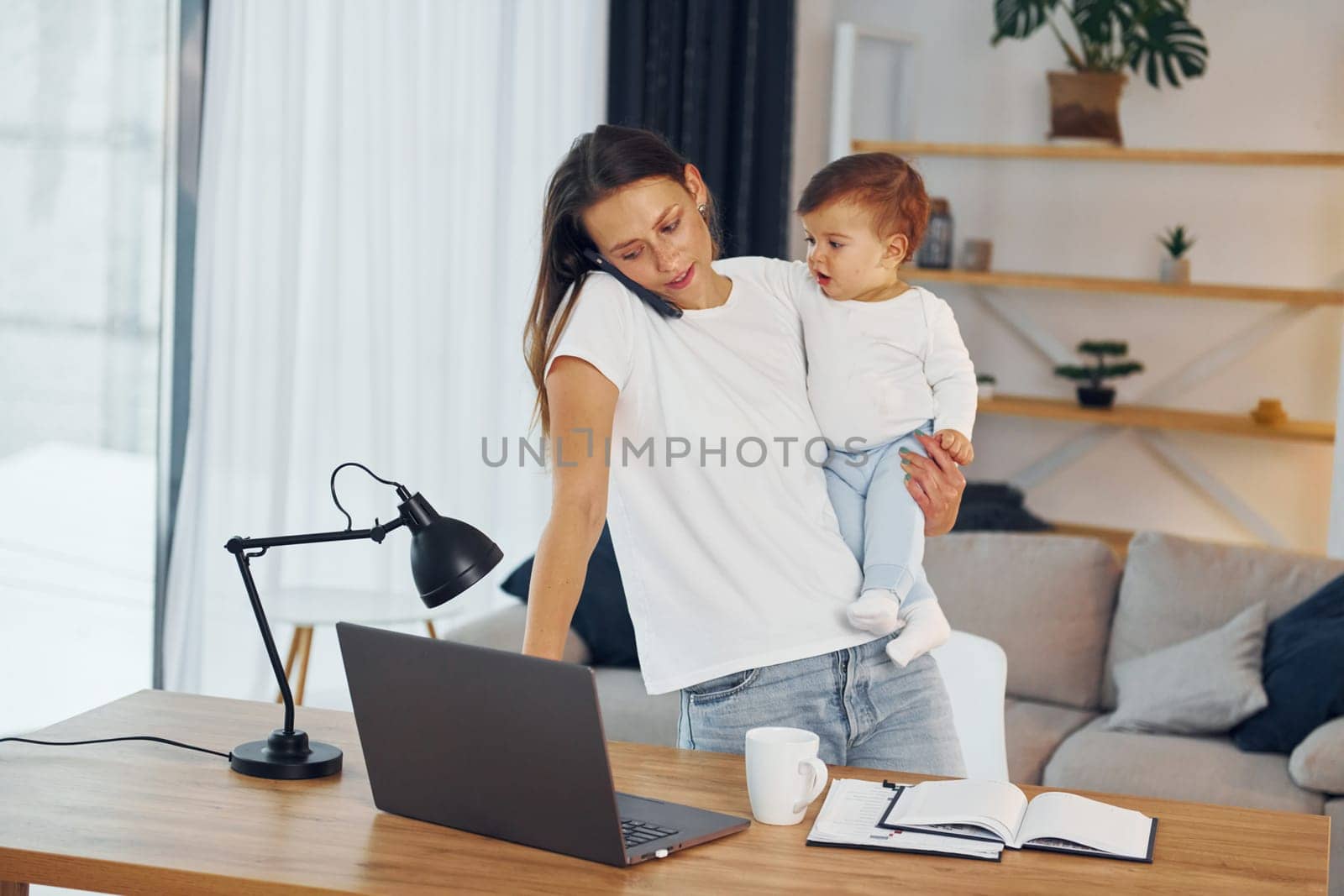 Using laptop. Mother with her little daughter is at home together.