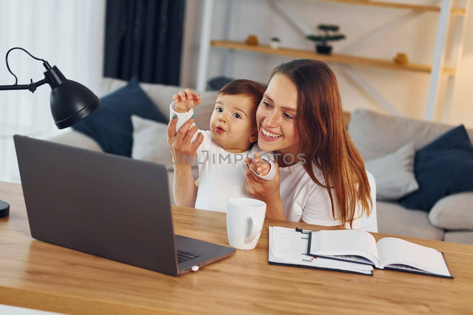 Watching movie by using laptop. Mother with her little daughter is at home together.