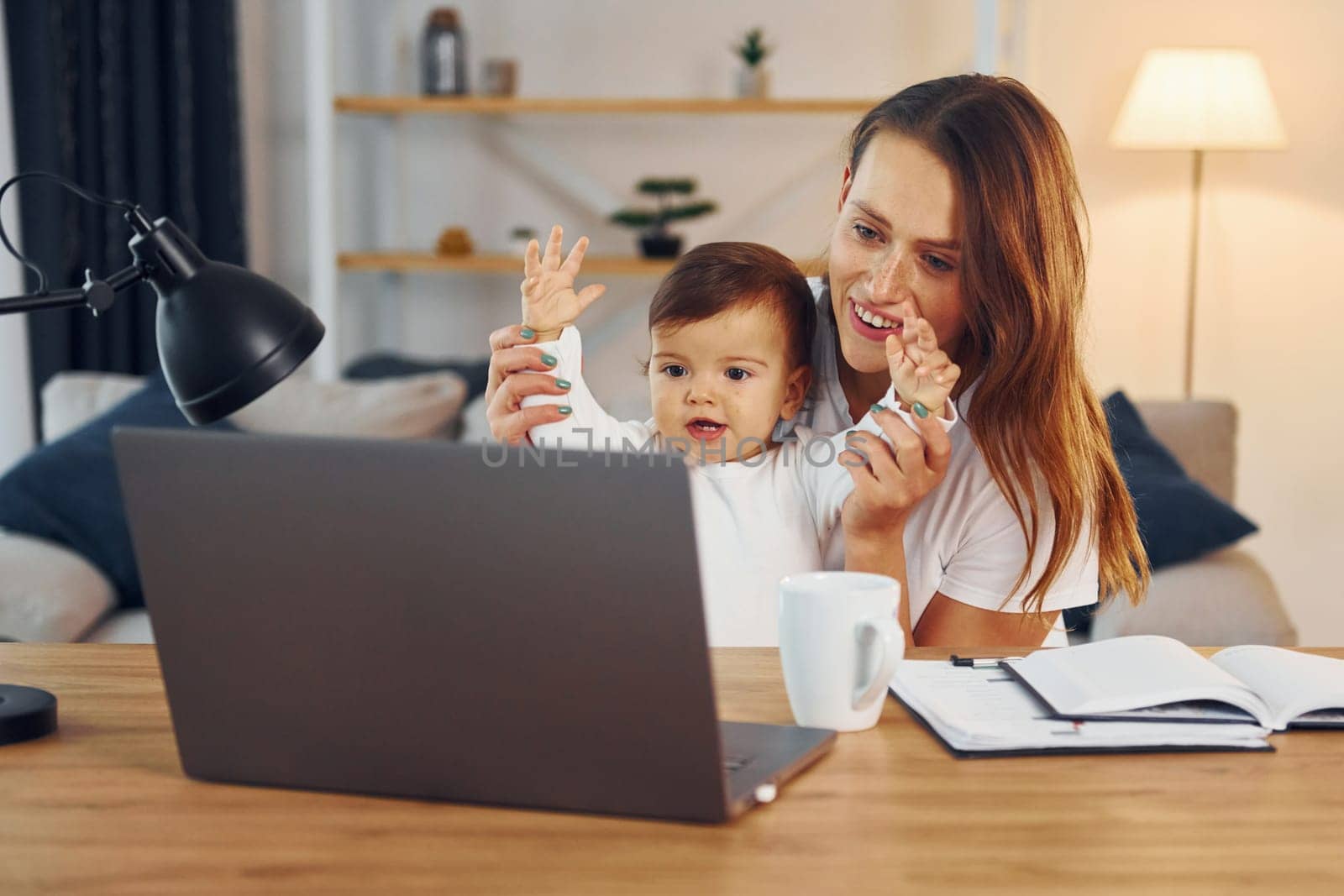 Watching movie by using laptop. Mother with her little daughter is at home together.