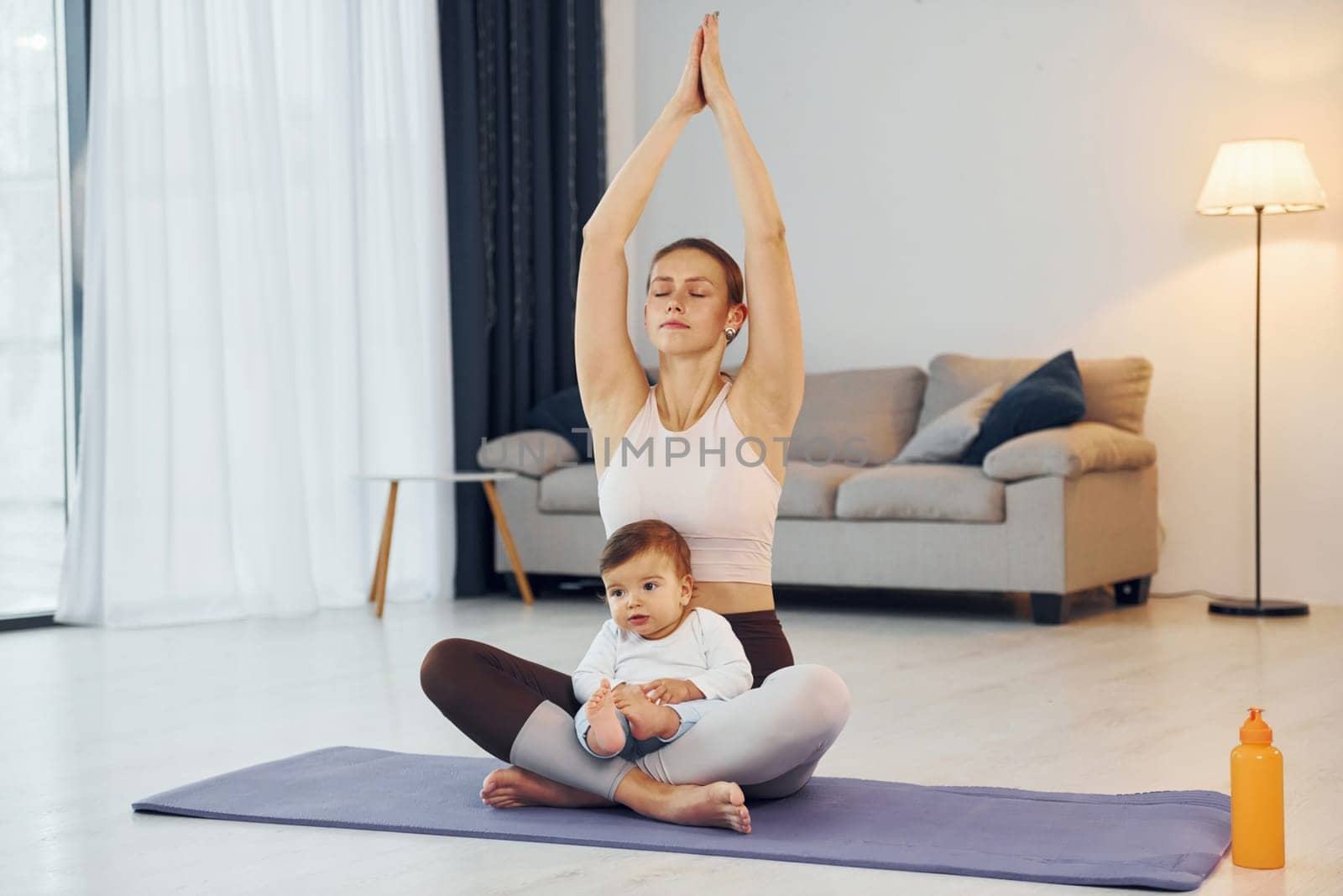 Doing yoga exercises. Mother with her little daughter is at home together by Standret