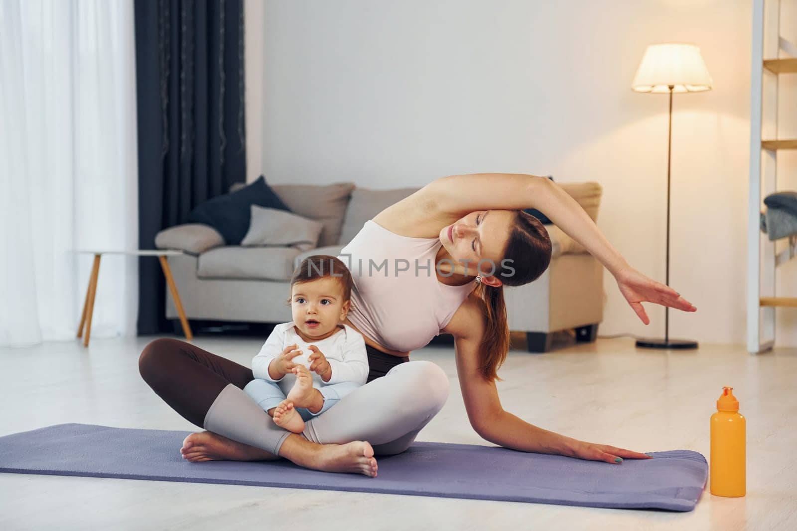 Doing yoga exercises. Mother with her little daughter is at home together.