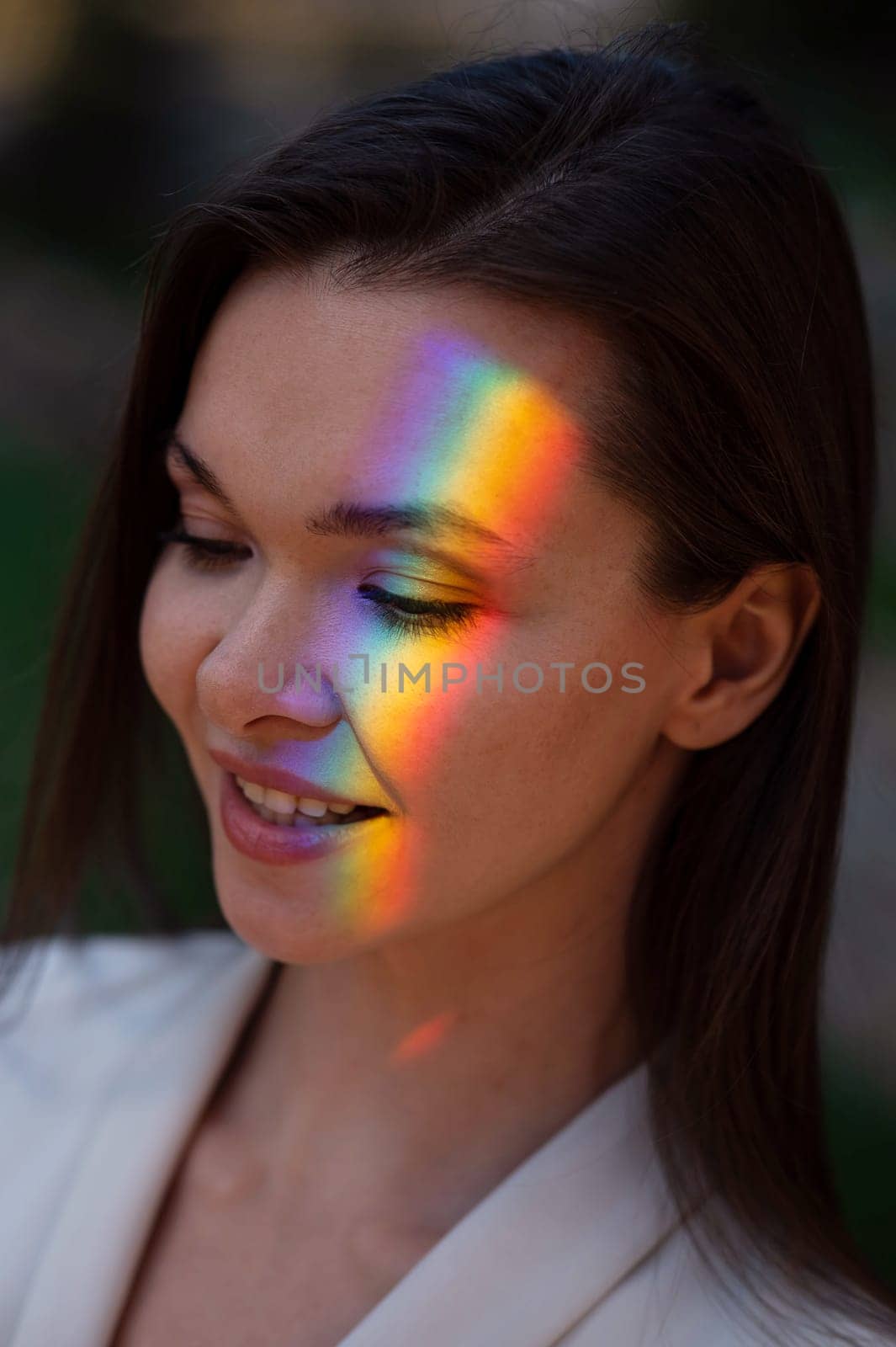 Portrait of caucasian woman with rainbow beam on her face outdoors