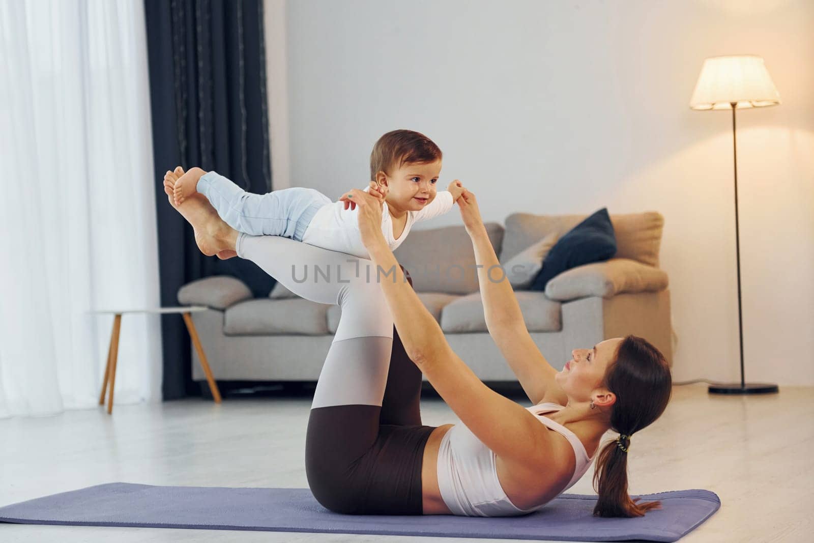 Doing fitness together. Mother with her little daughter is at home together by Standret