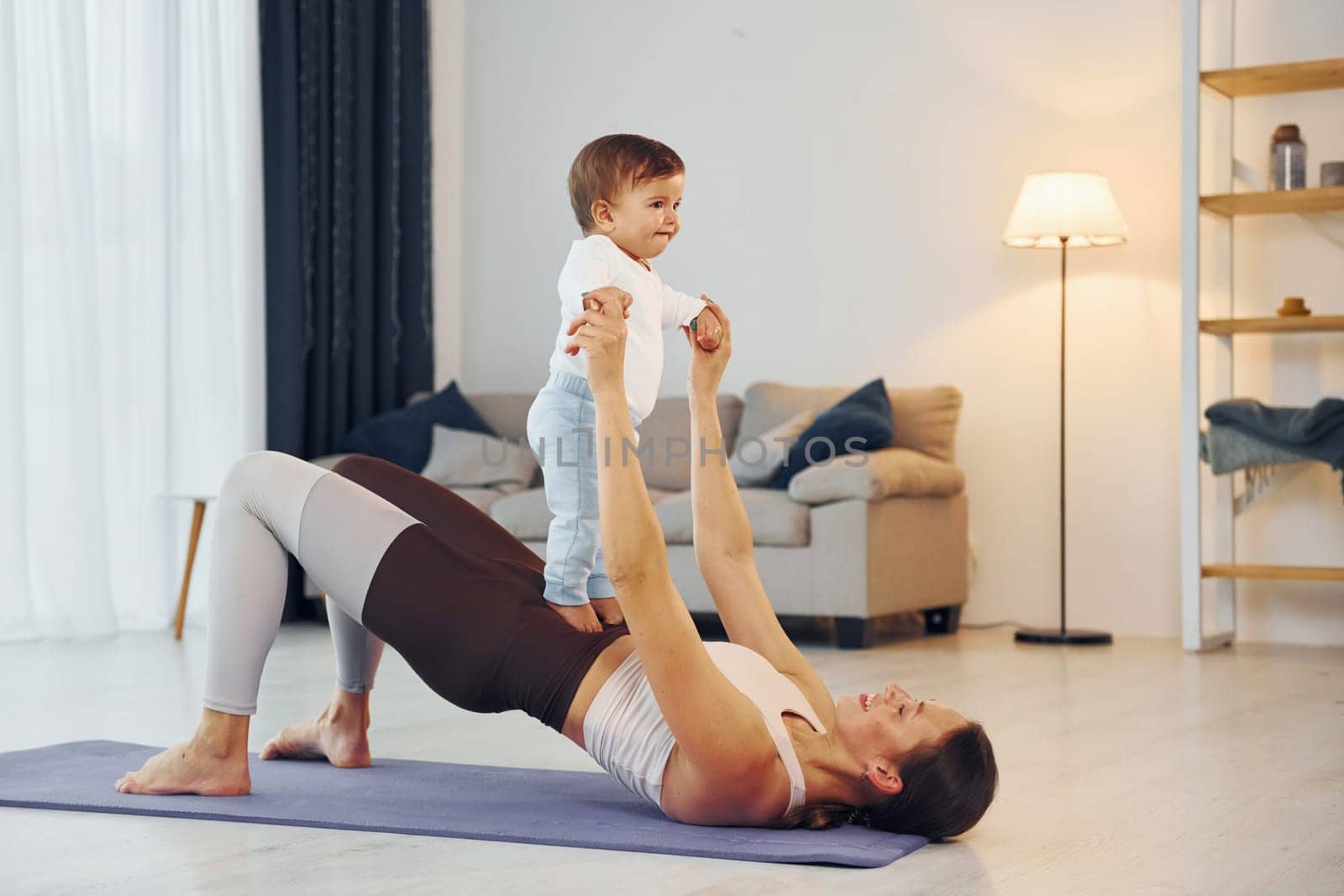 Doing fitness together. Mother with her little daughter is at home together.