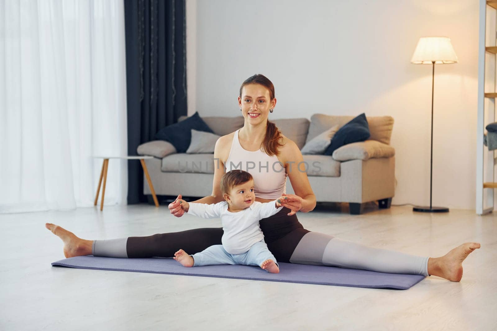 Doing fitness together. Mother with her little daughter is at home together.