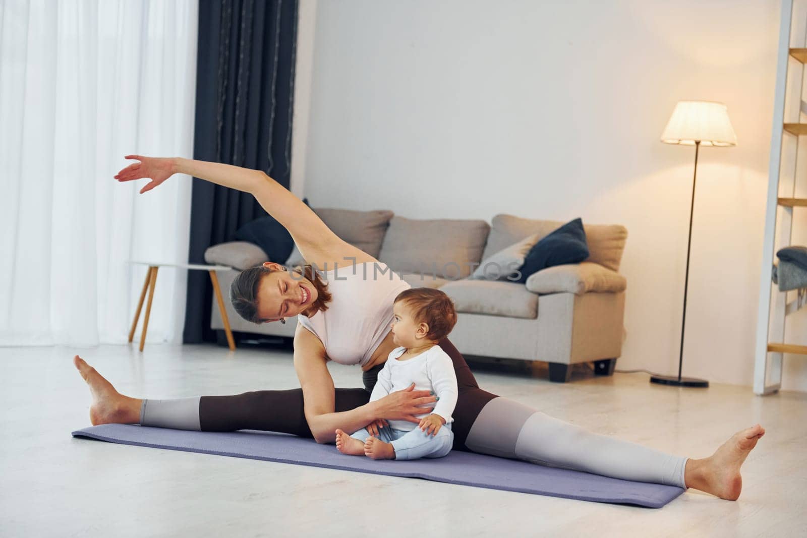 Doing fitness together. Mother with her little daughter is at home together.