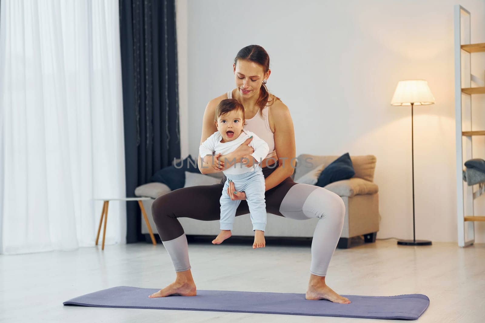 Teaching fitness. Mother with her little daughter is at home together by Standret