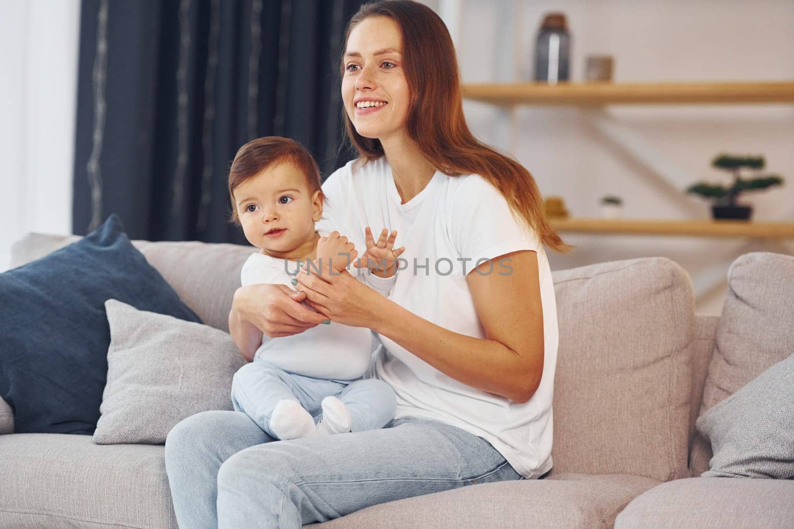 Sitting on the sofa. Mother with her little daughter is at home together.