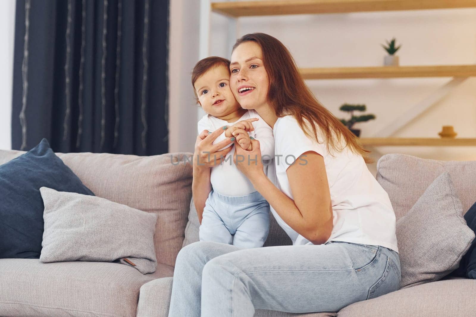 Sitting on the sofa. Mother with her little daughter is at home together.