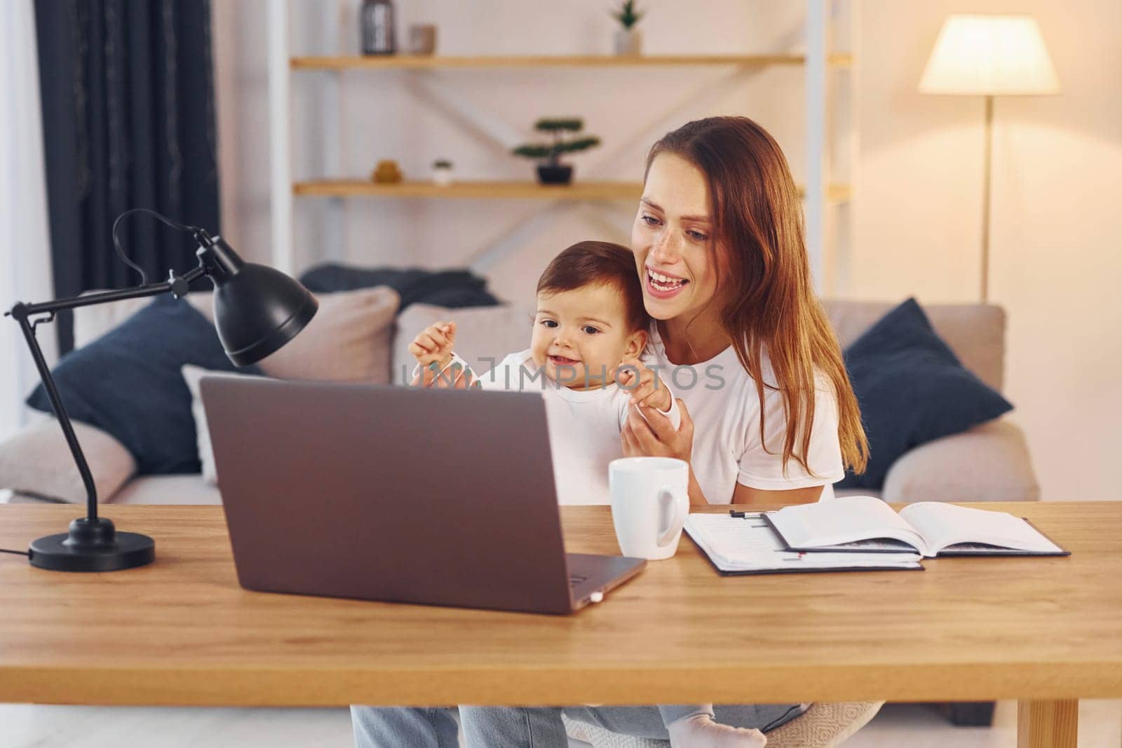 Watching movie by using laptop. Mother with her little daughter is at home together.