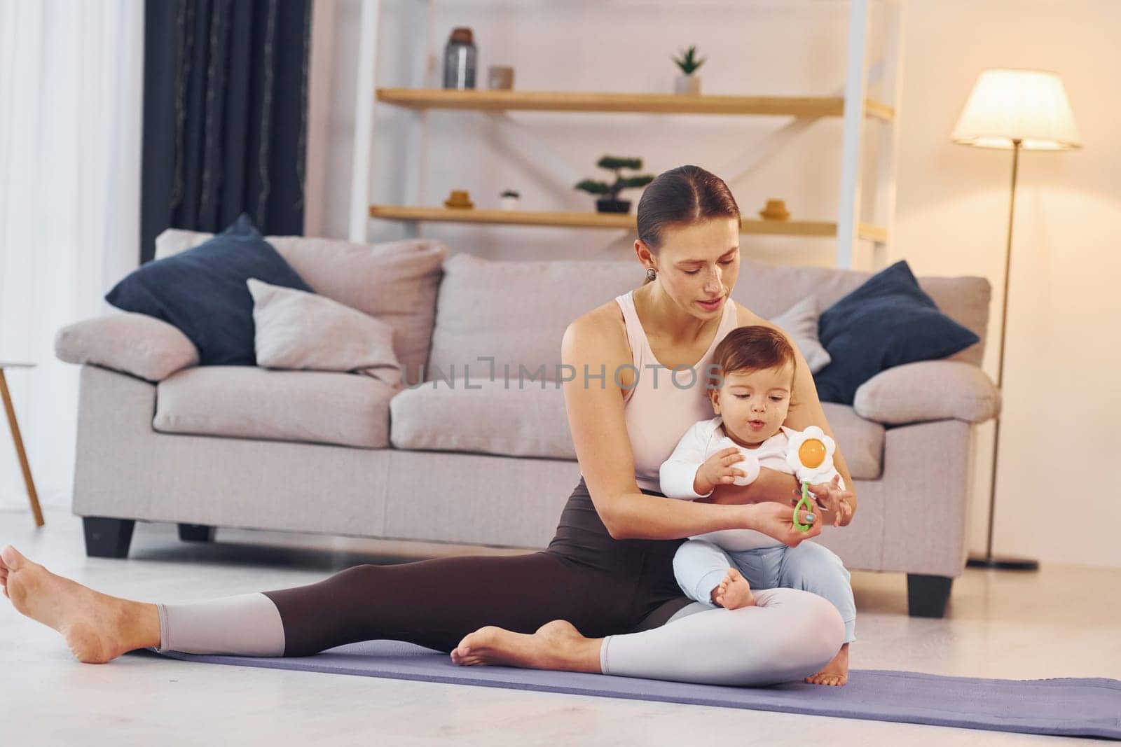 On the yoga mat. Mother with her little daughter is at home together.