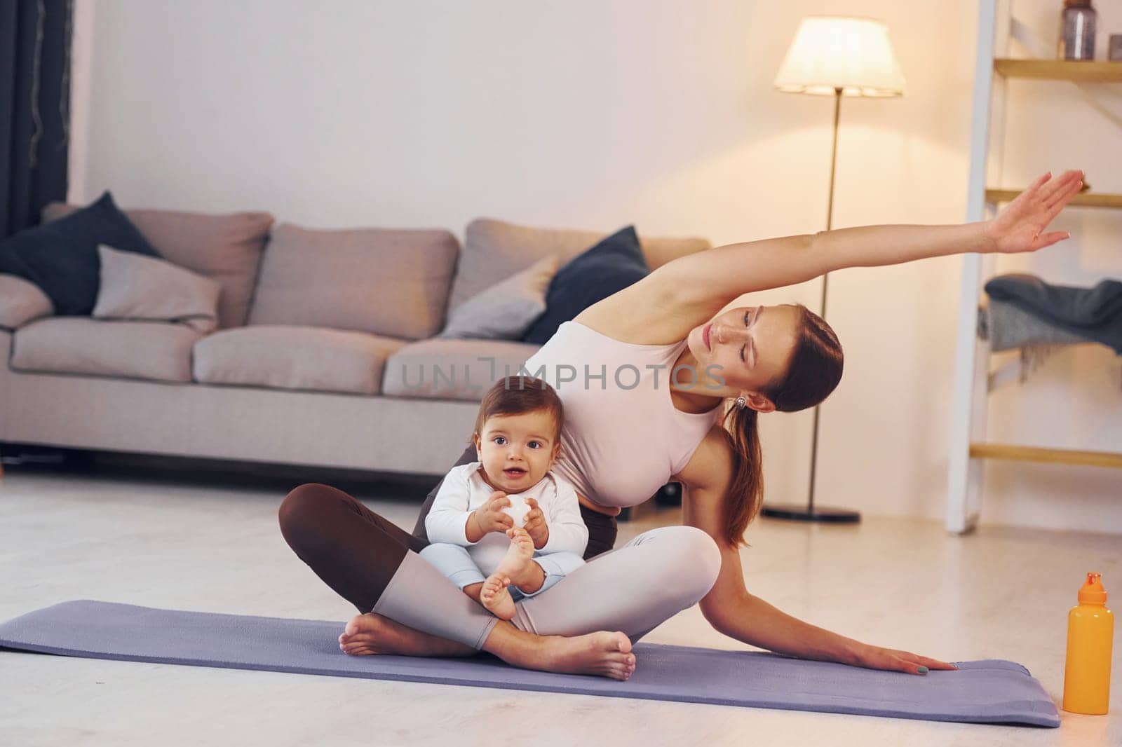 On the yoga mat. Mother with her little daughter is at home together by Standret