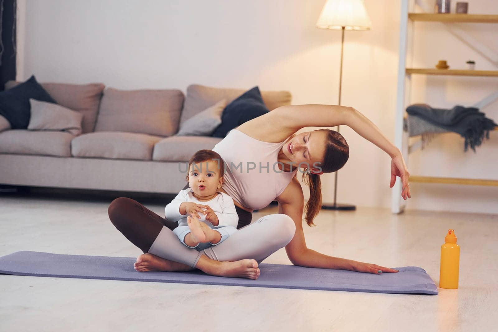 On the yoga mat. Mother with her little daughter is at home together by Standret