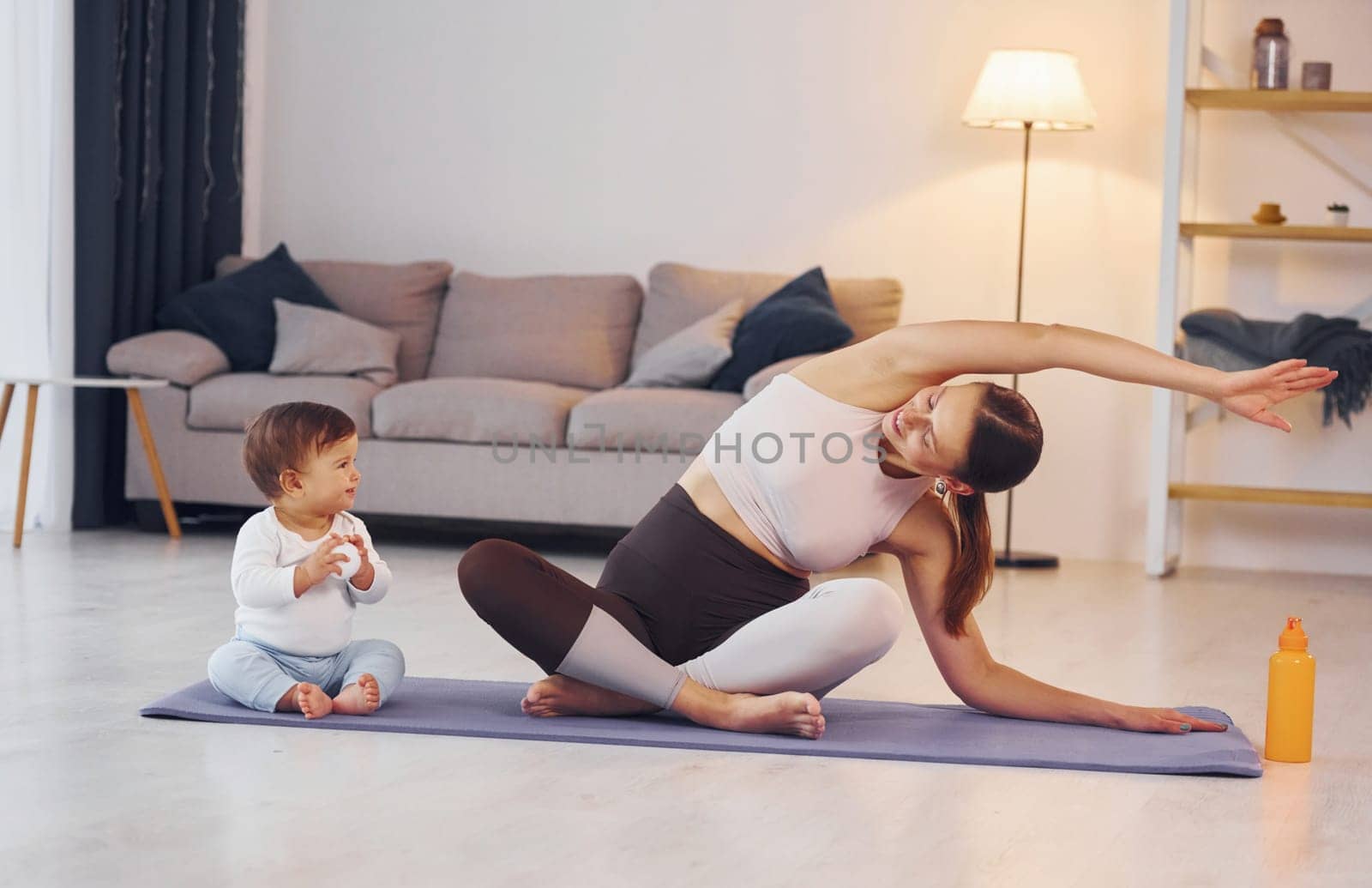 Practicing yoga. Mother with her little daughter is at home together.