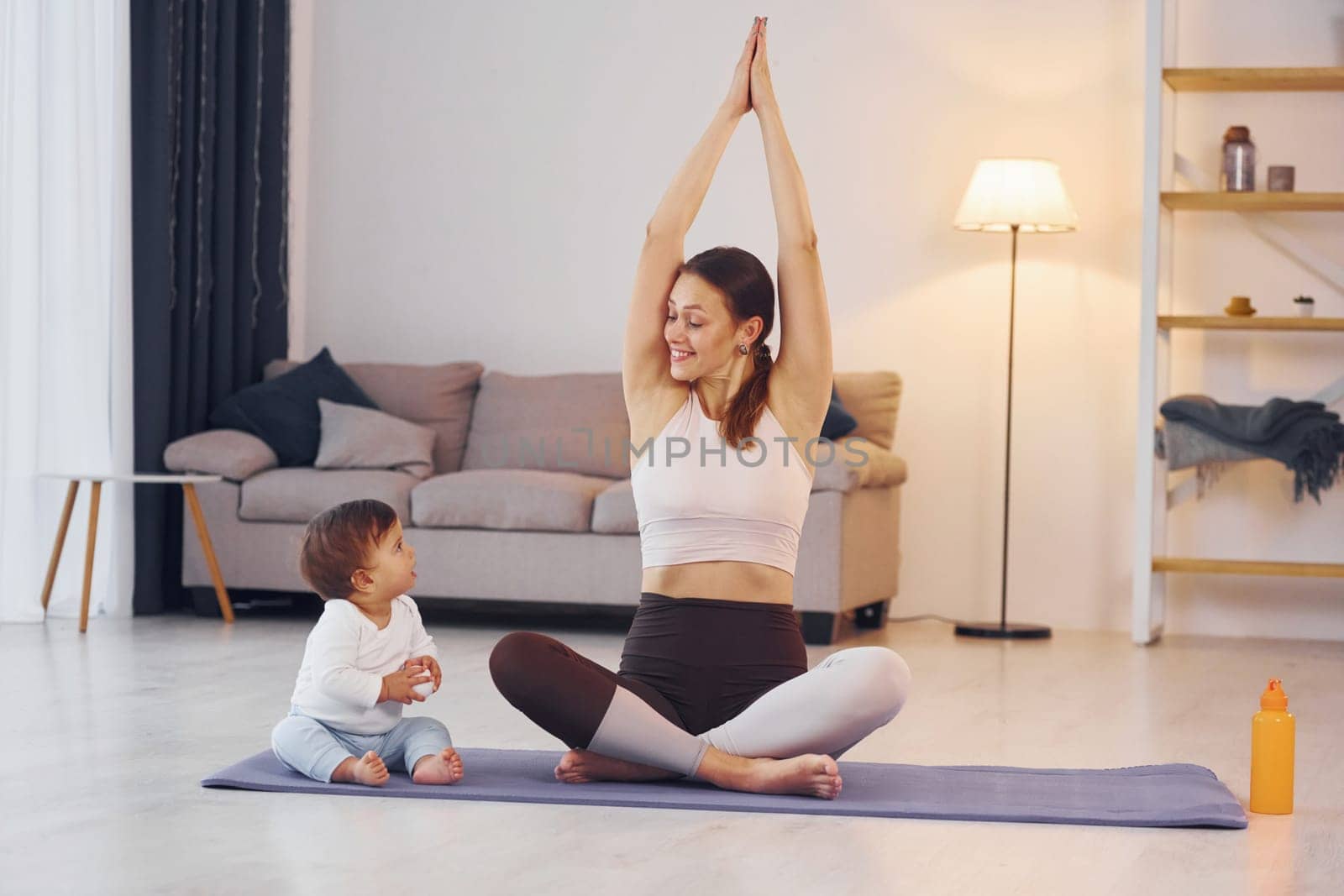 Practicing yoga. Mother with her little daughter is at home together.