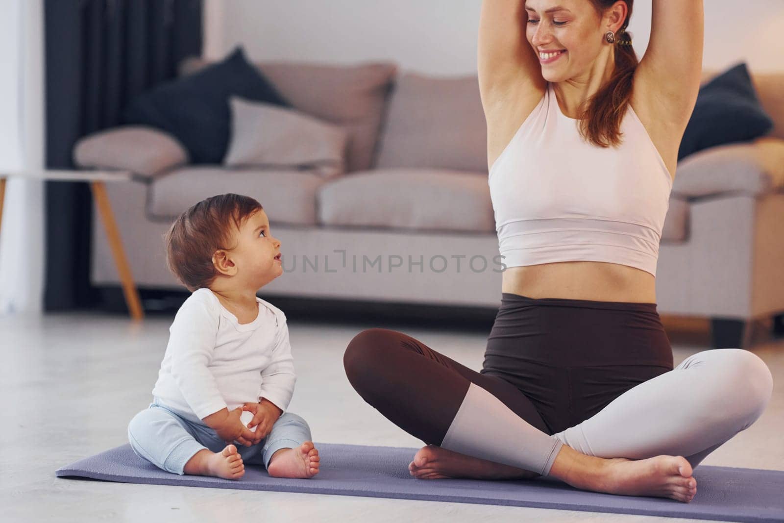 Practicing yoga. Mother with her little daughter is at home together.