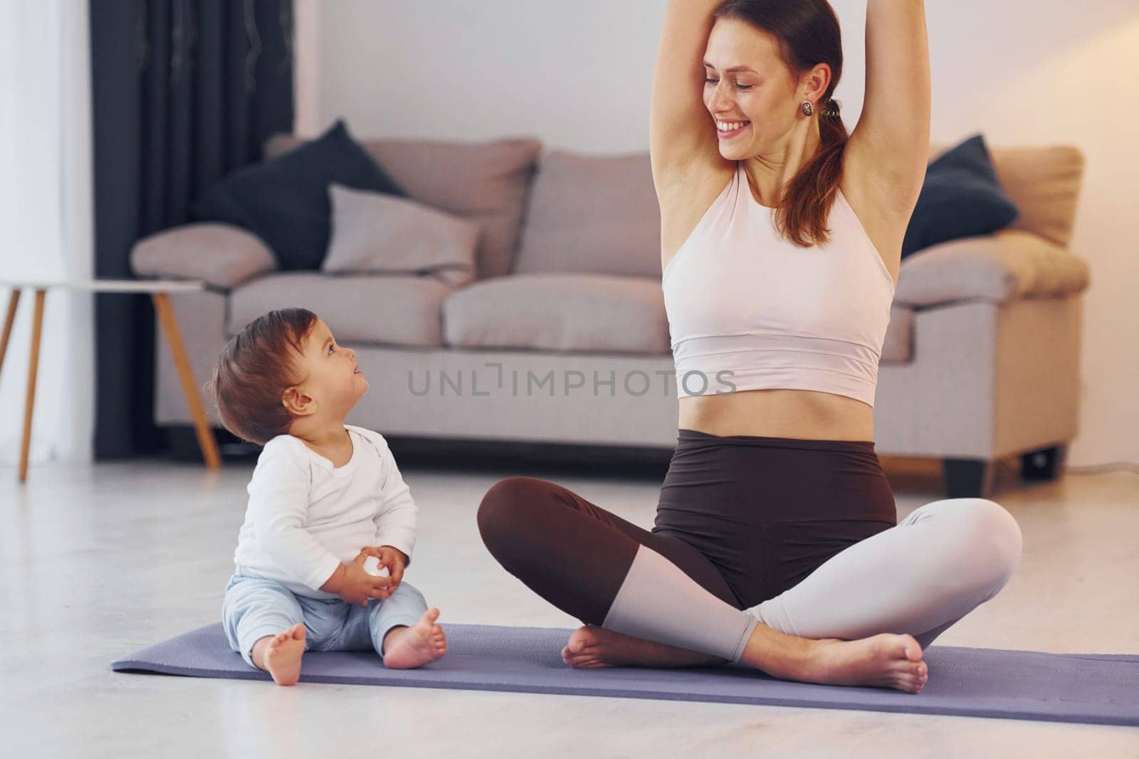 Practicing yoga. Mother with her little daughter is at home together.