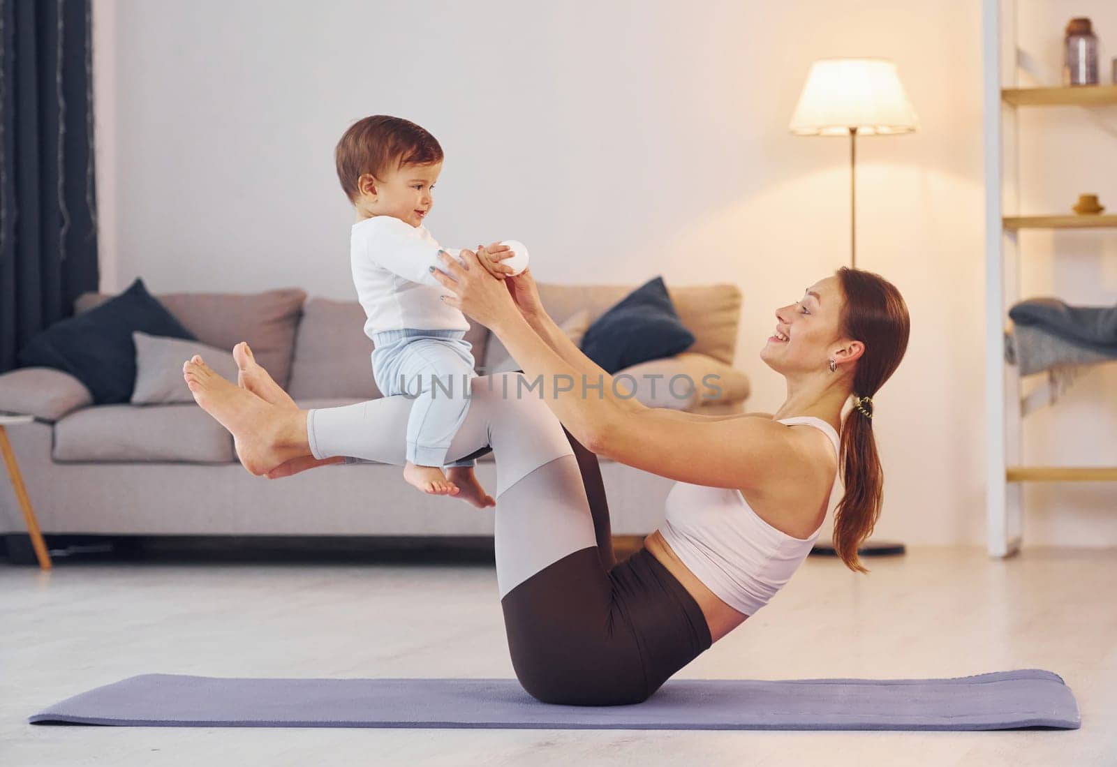 Side view of woman that doing exercises with little girl. Mother with her little daughter is at home together.