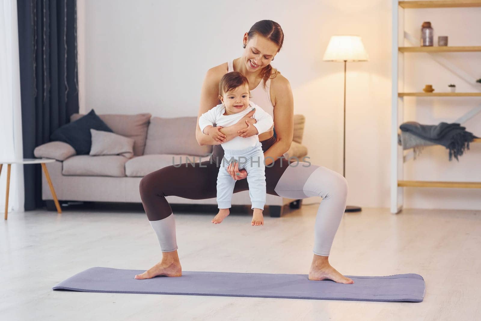Teaching fitness. Mother with her little daughter is at home together by Standret