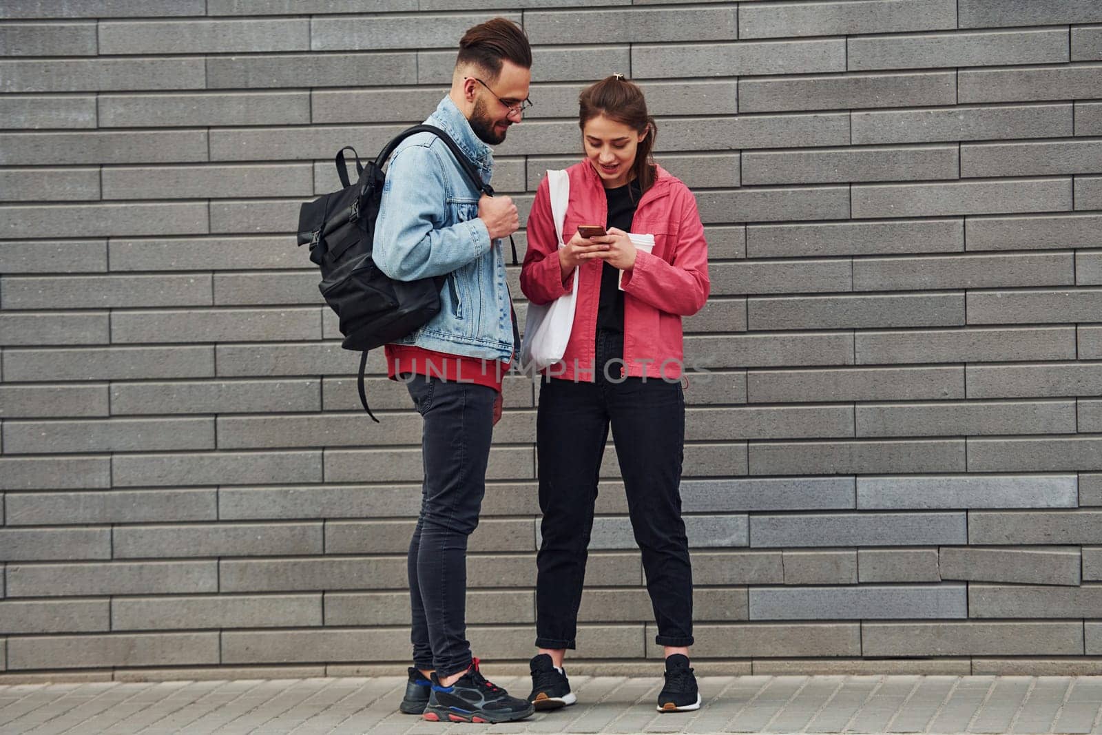 Young stylish man with woman in casual clothes outdoors together. Conception of friendship or relationships.