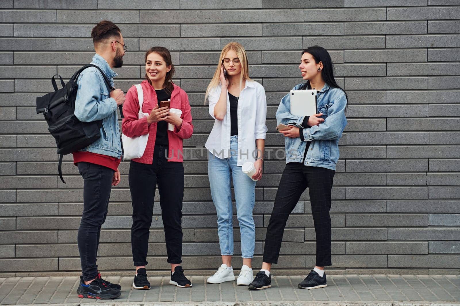 Three women and one guy is outdoors near building at daytime.