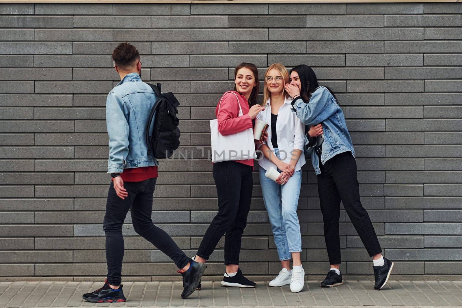 Three women and one guy is outdoors near building at daytime.