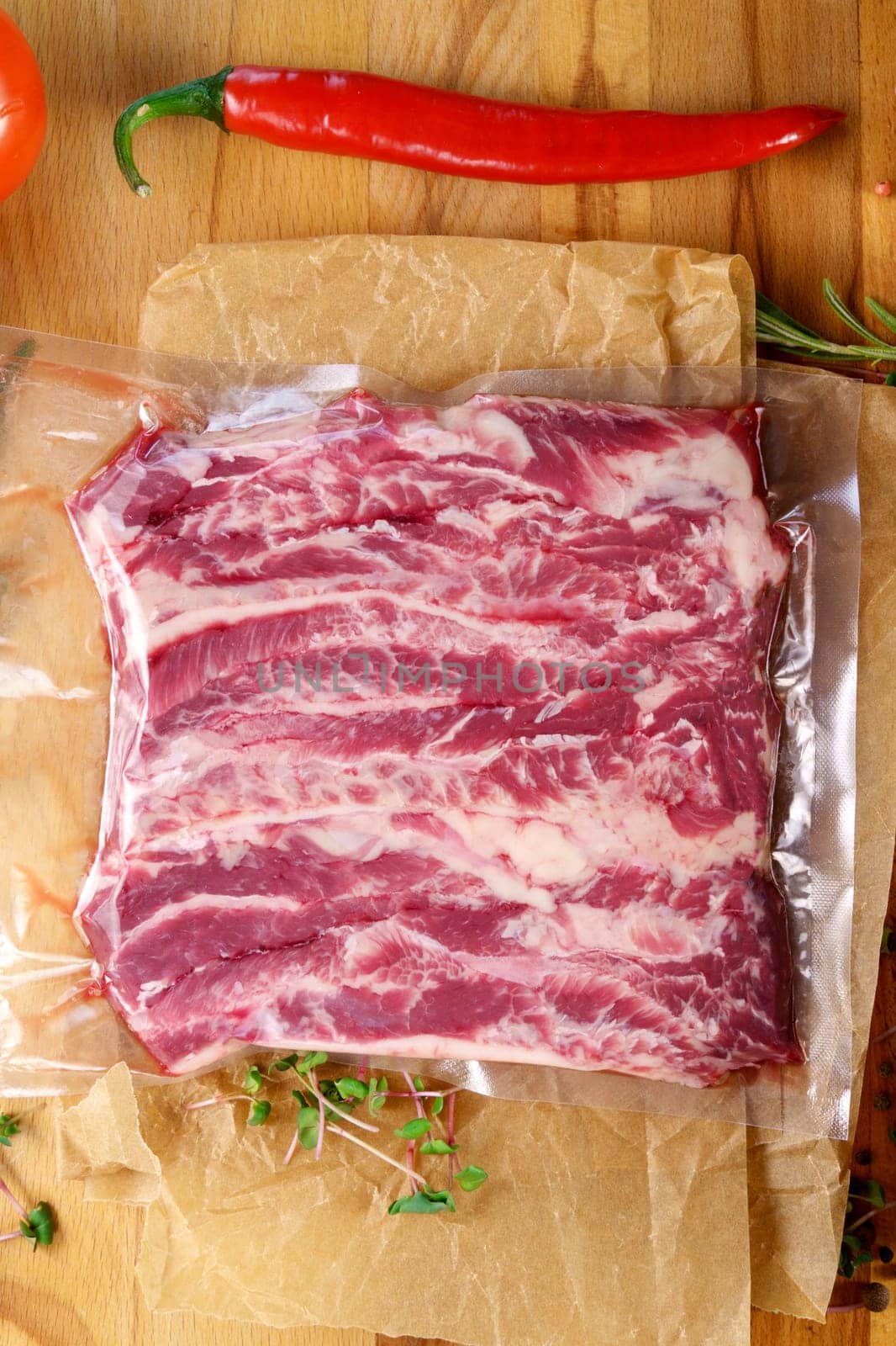 Vacuum packed meat, on a wooden board, steak. Top view. Various spices. Vertical photo by darksoul72