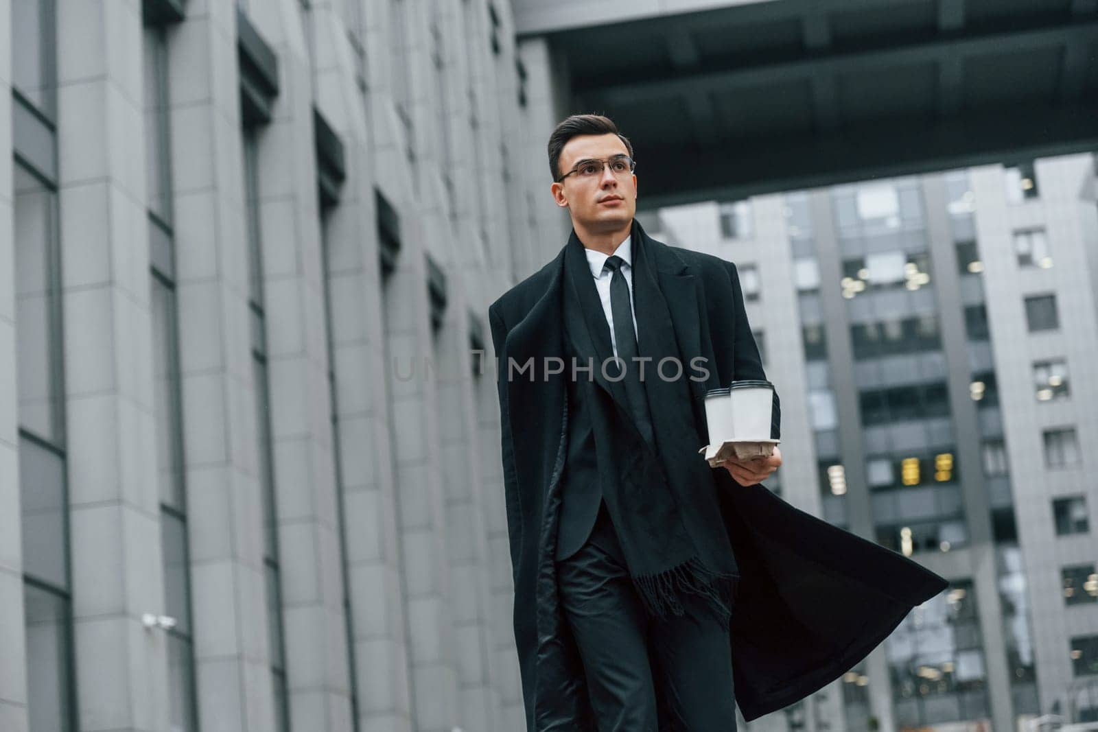 Walking forward. Businessman in black suit and tie is outdoors in the city by Standret