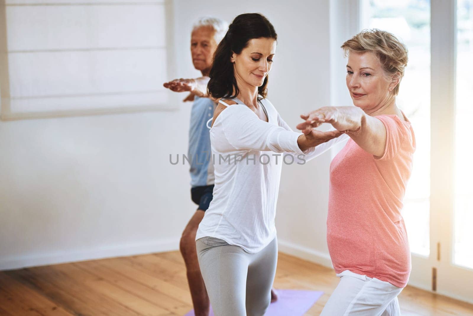 Yoga is their secret to staying fit. a teacher helping a senior woman during a yoga class. by YuriArcurs