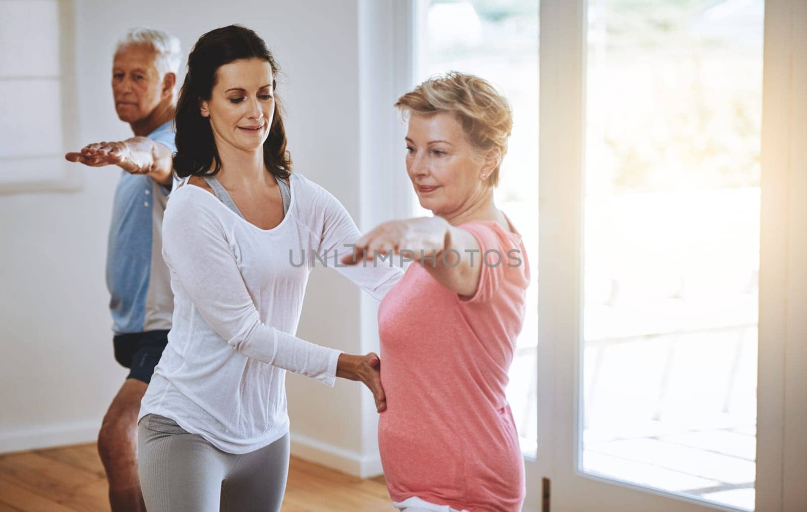 Living a healthy lifestyle through yoga. a teacher helping a senior woman during a yoga class