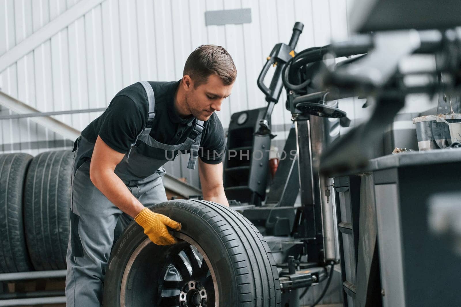 Replacement of the old tire. Man in uniform is working in the auto service.