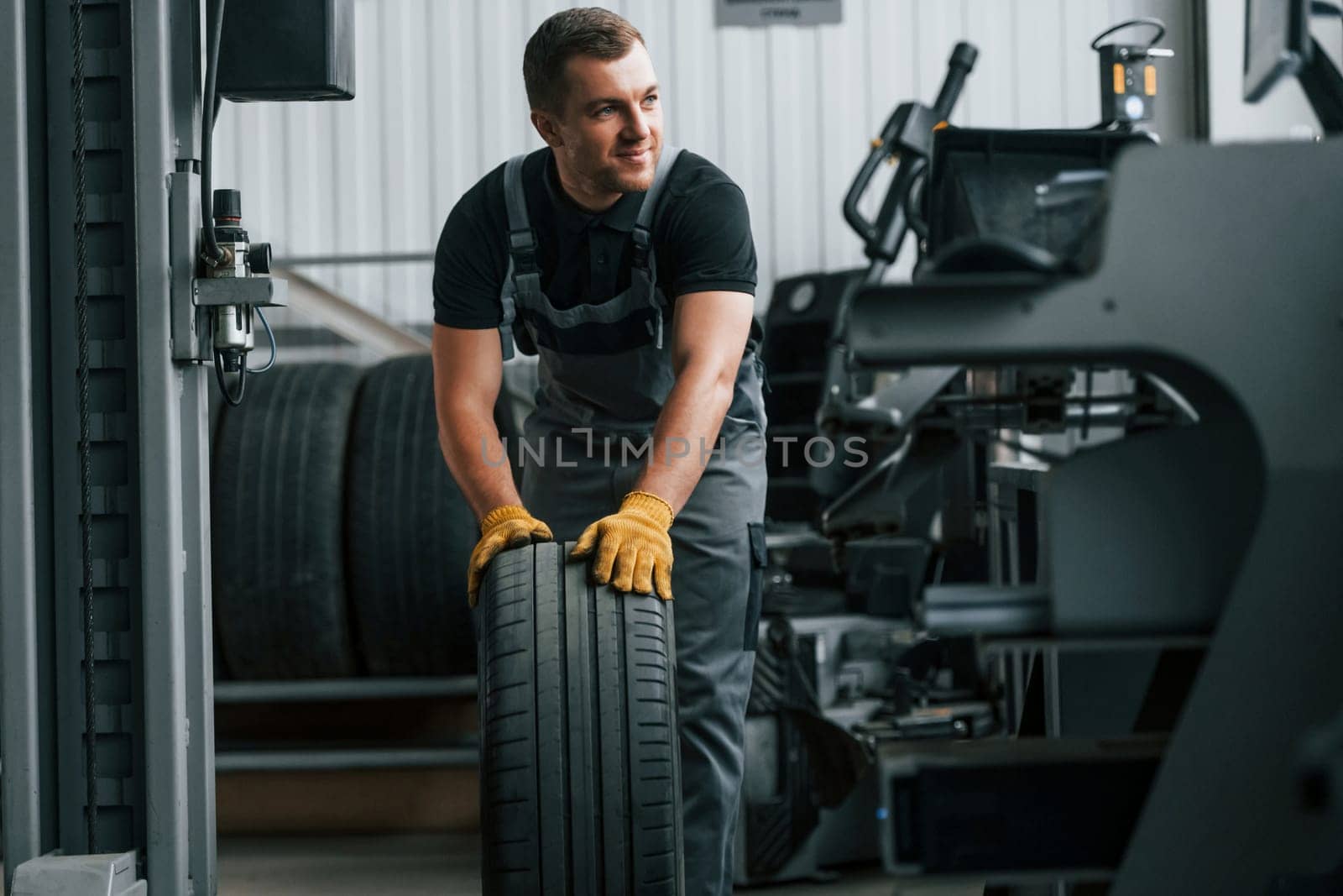 In uniform. Man is working in the auto service.