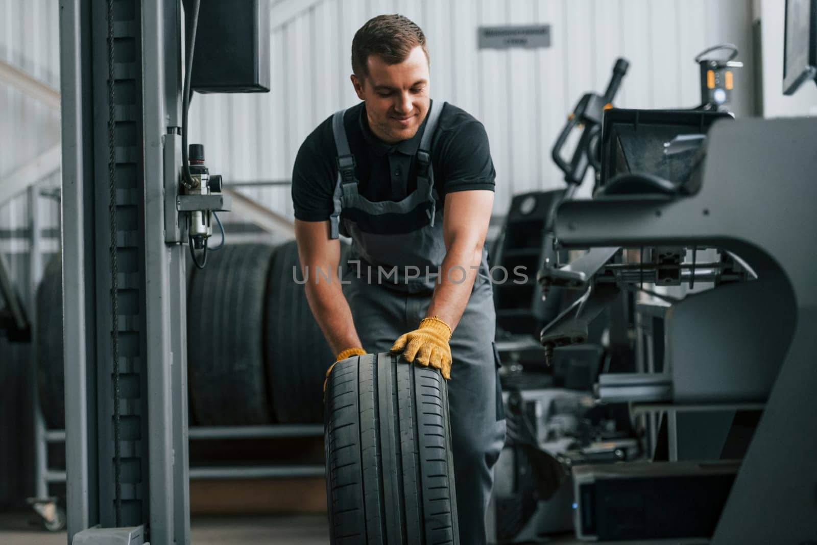 In uniform. Man is working in the auto service.
