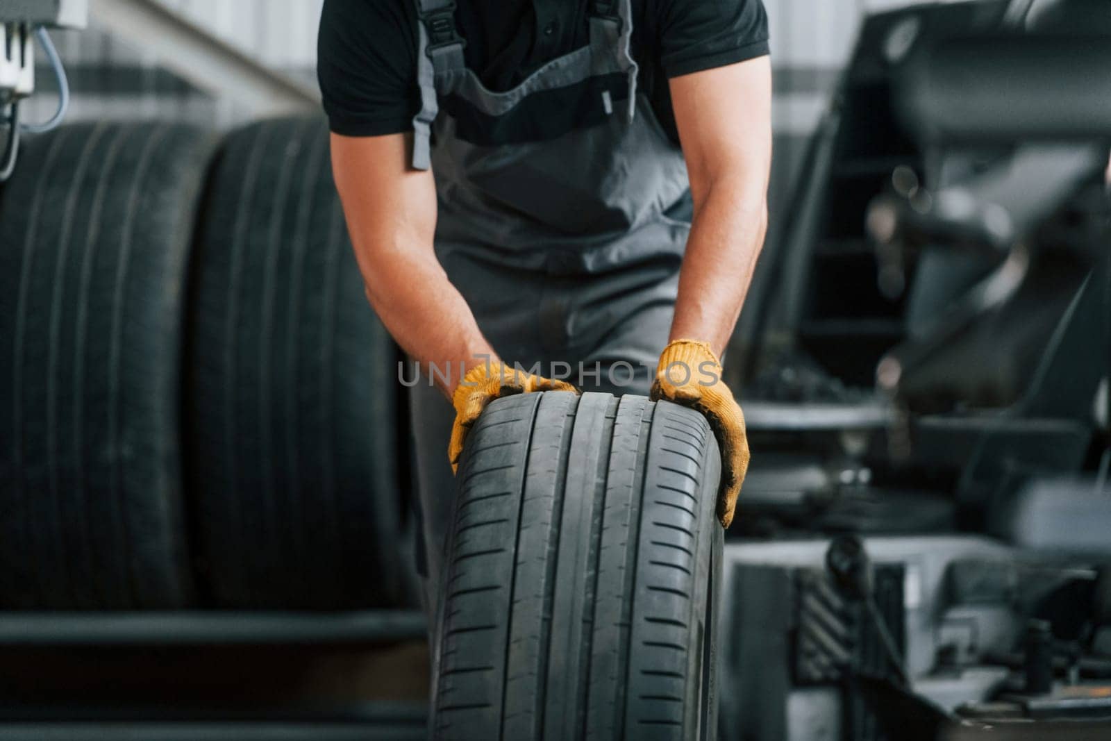 Front view. Man in uniform is working in the auto service.