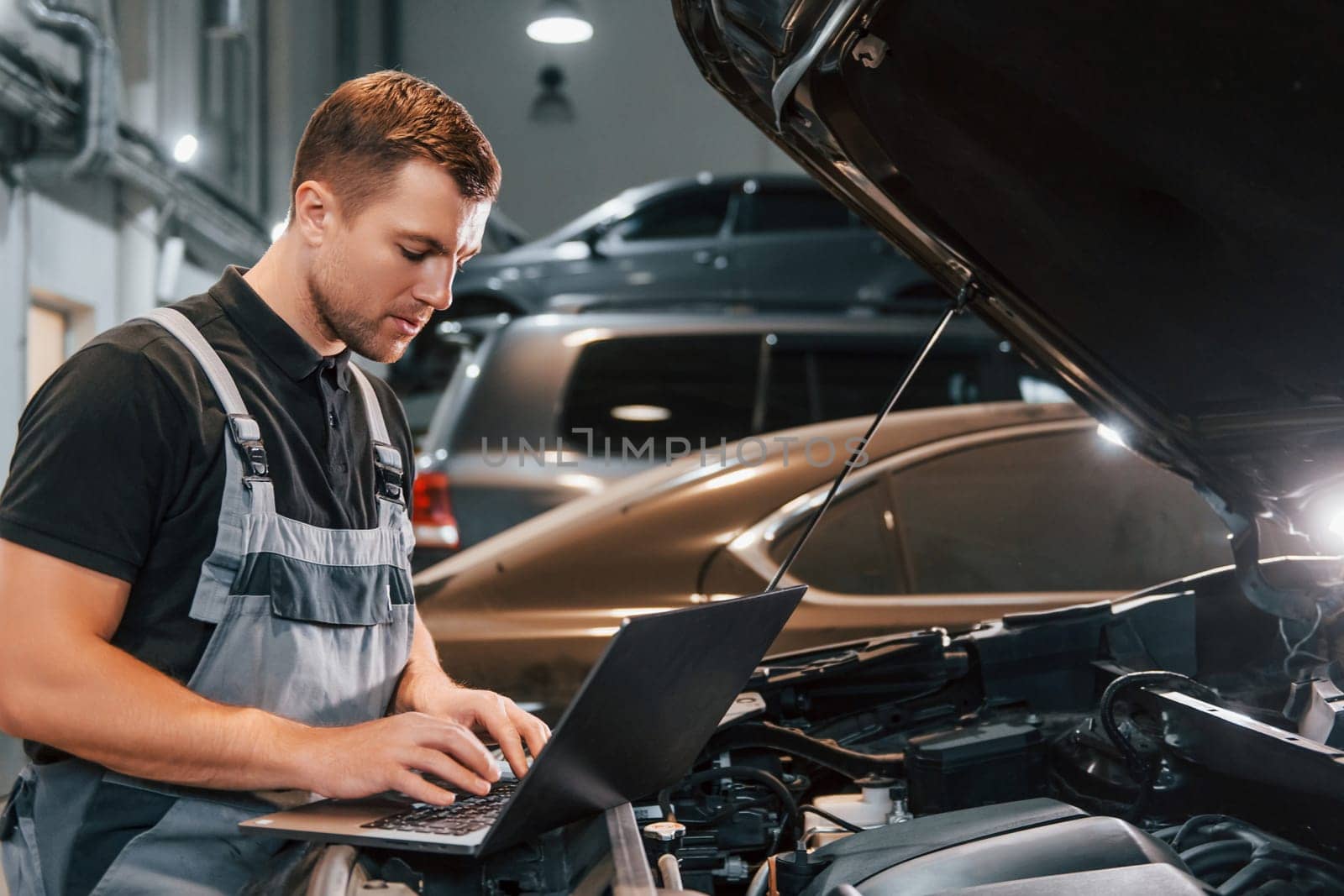 Side view. Man in uniform is working in the auto service.
